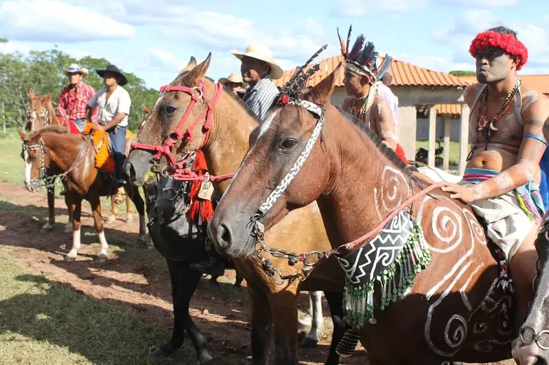 Guerreiros Kadiwéu a cavalo com pintura corporal e animal